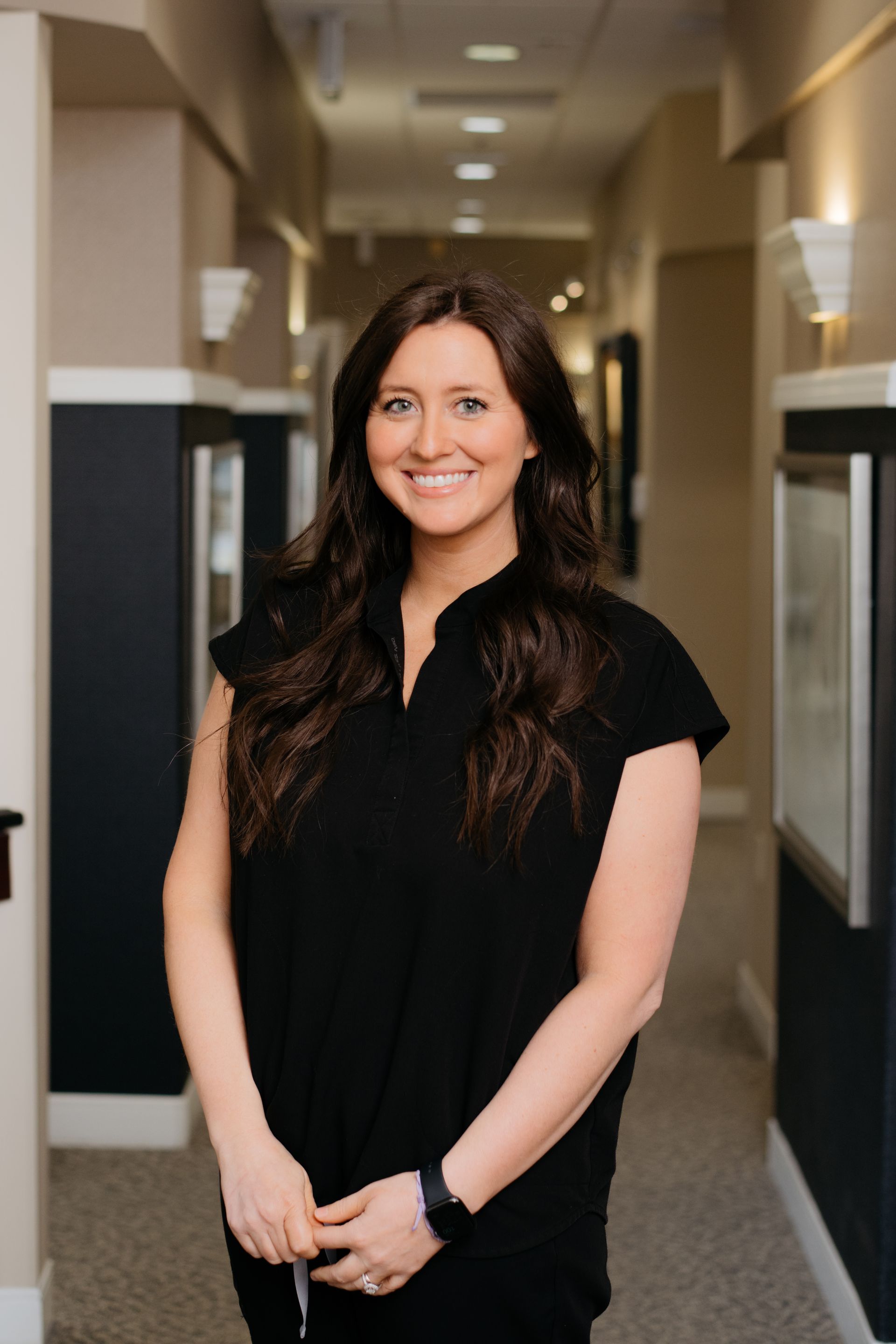 A woman in a black shirt is standing in a hallway.