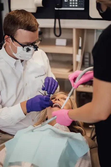 A dentist is examining a woman 's teeth in a dental office.