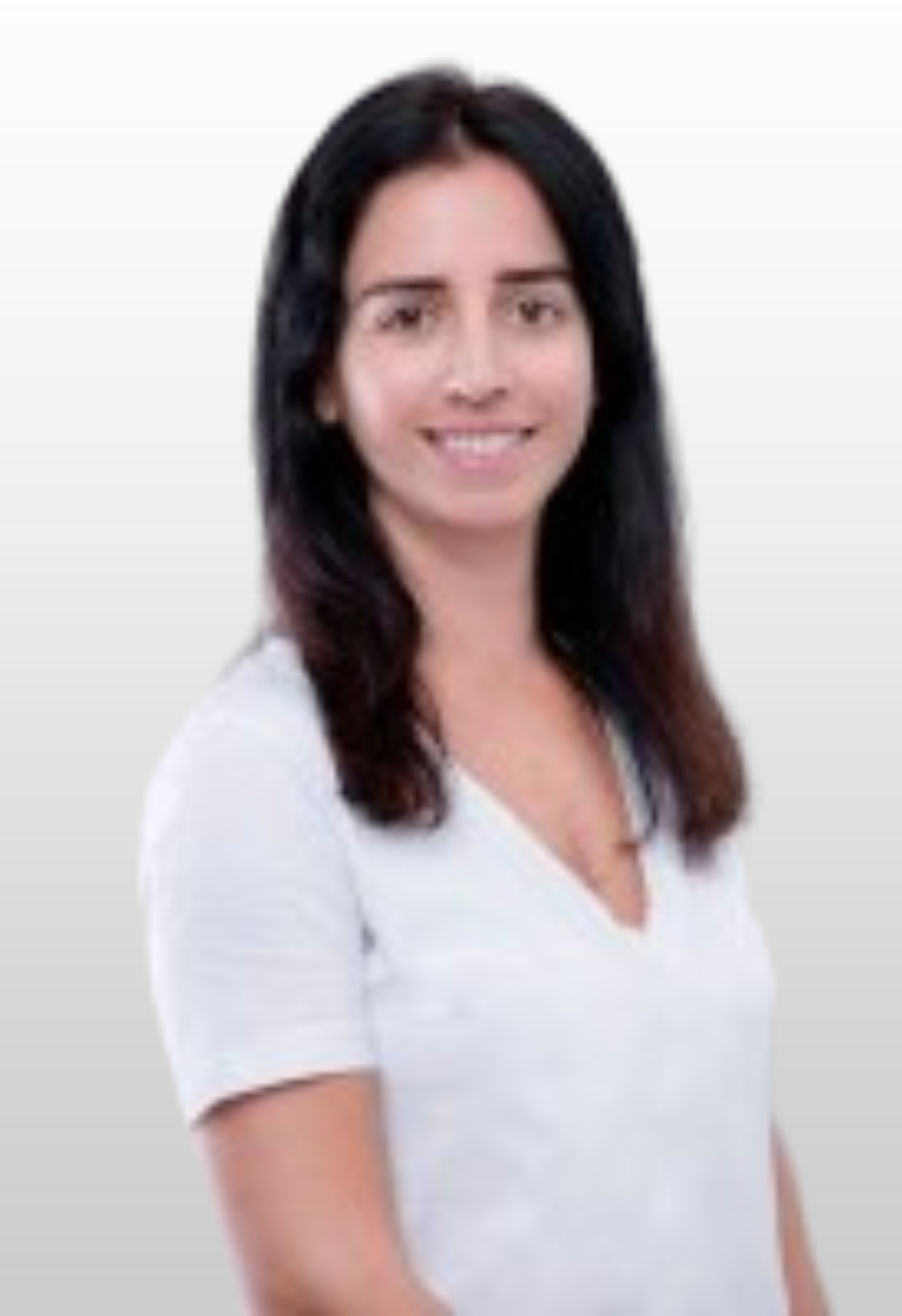 A woman with long dark hair is wearing a white shirt and smiling.