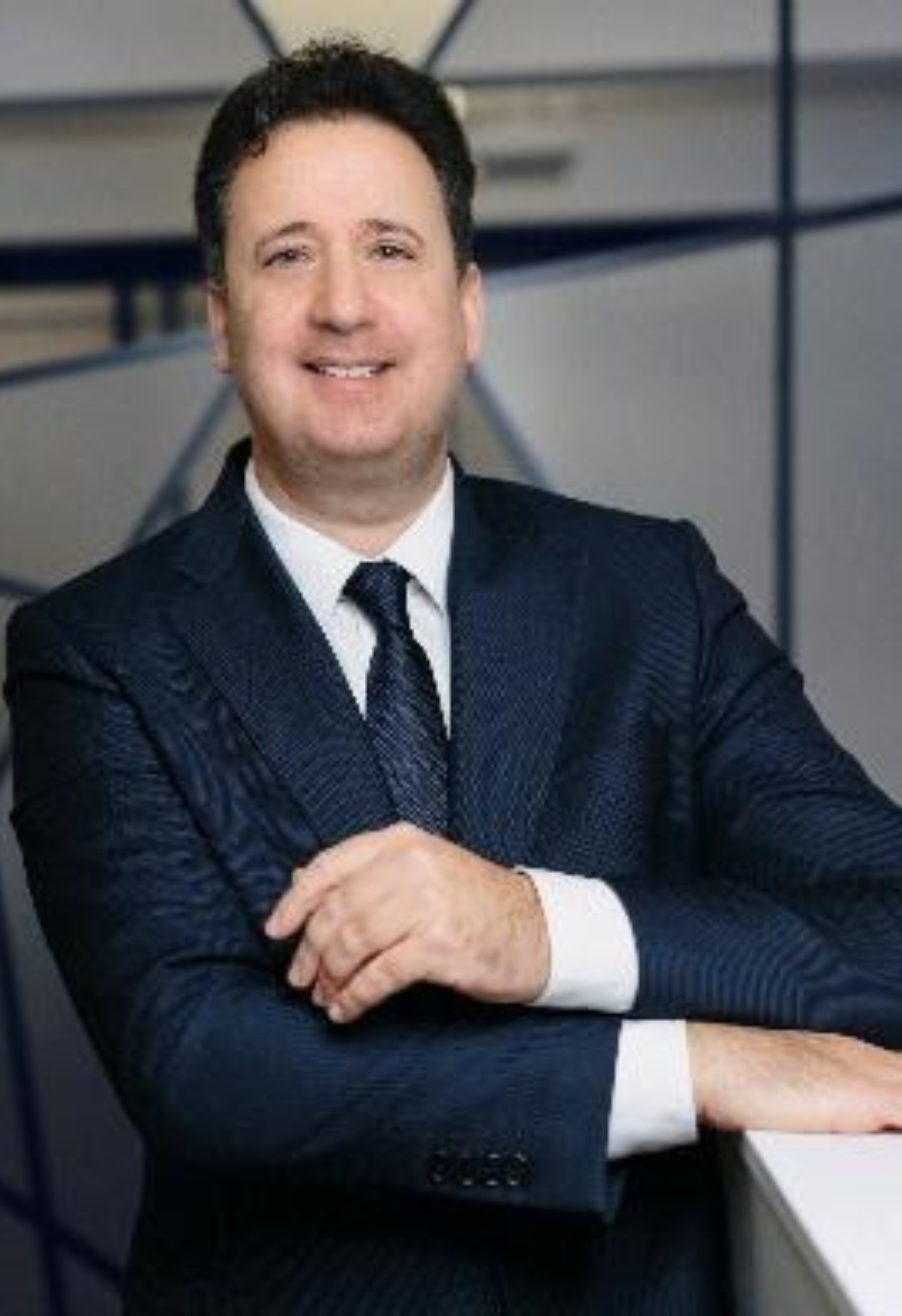 A man in a suit and tie is leaning on a counter.