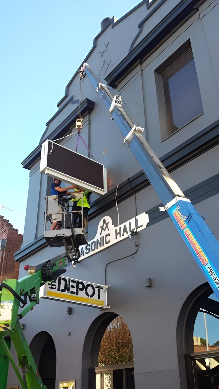 A Crane Is Lifting A Sign On The Side Of A Building — Newcastle Cranes In Lake Macquarie, NSW