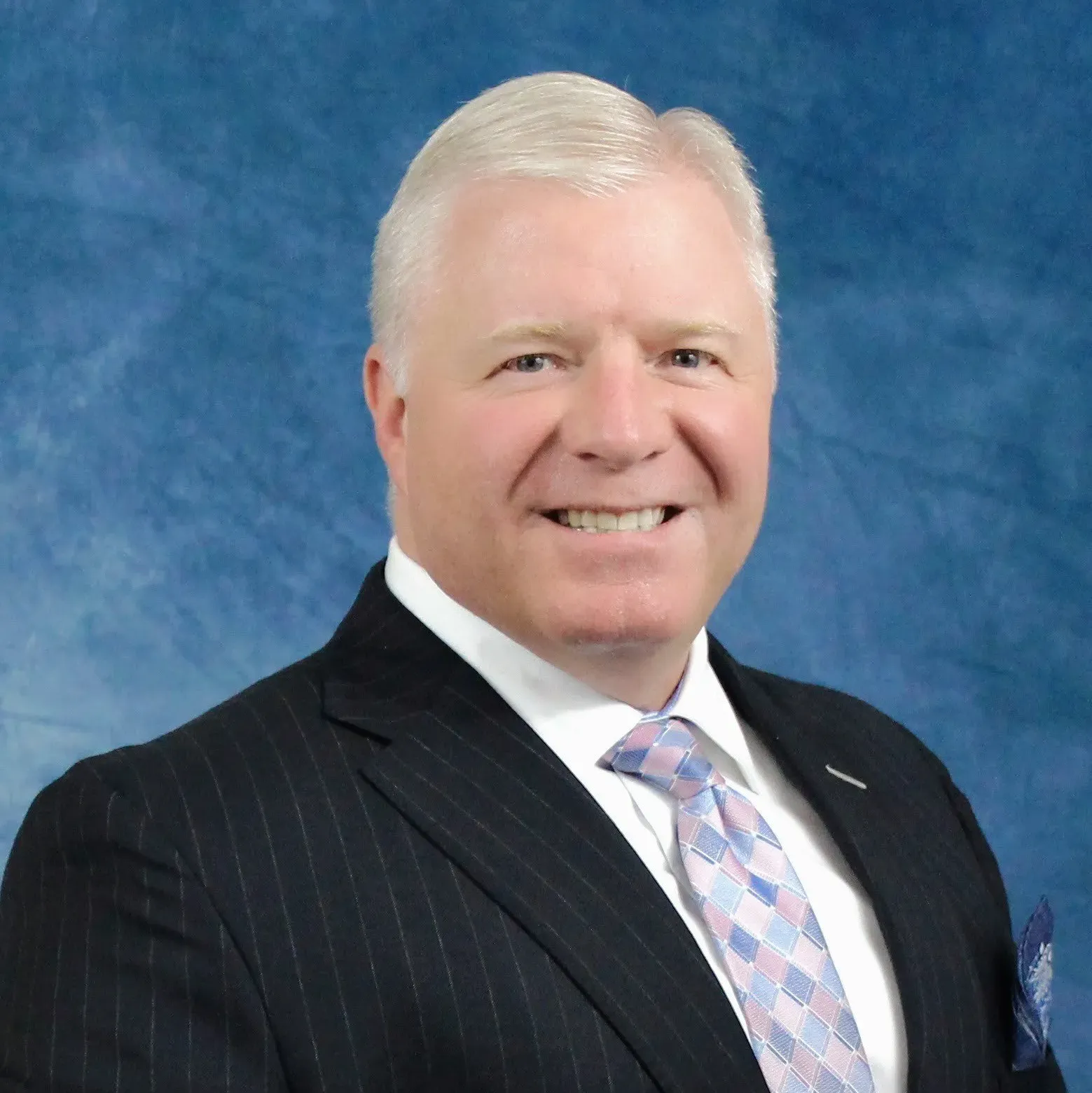 A man in a suit and tie is smiling for the camera