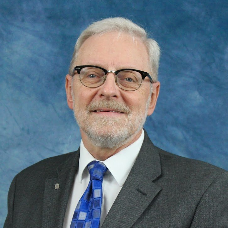A man in a suit and tie with glasses and a beard