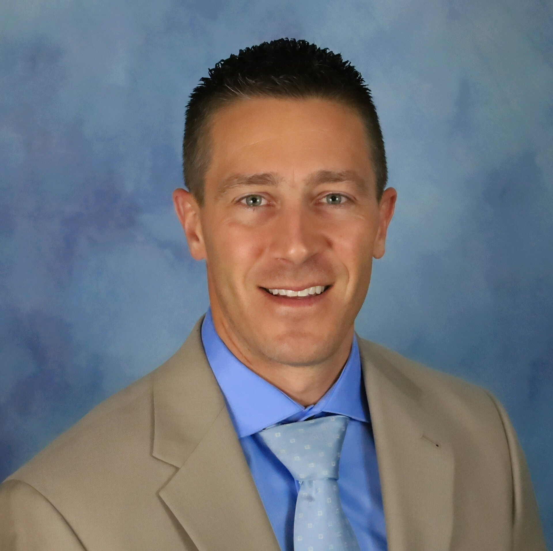 A man in a suit and tie smiles for the camera