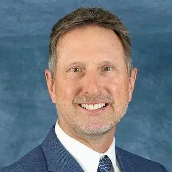 A man in a suit and tie is smiling for the camera.