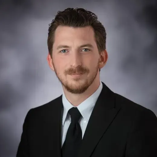 A man with a beard is wearing a suit and tie.