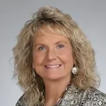 A woman with blonde hair and earrings is smiling for the camera.