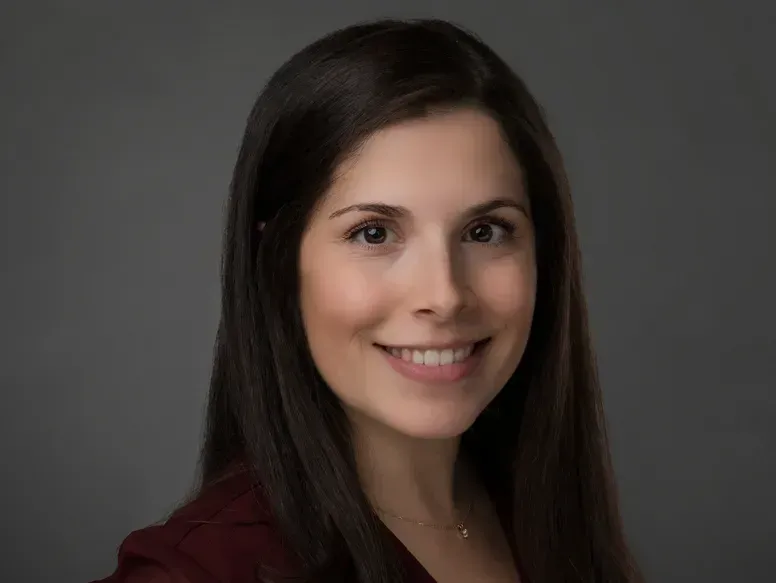 A woman with long dark hair is smiling for the camera.
