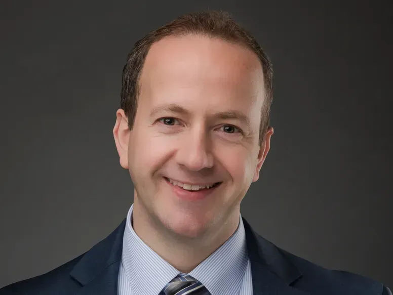 A man in a suit and tie is smiling for the camera.