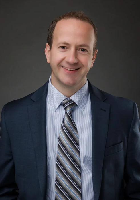 A man in a suit and tie is smiling for the camera.