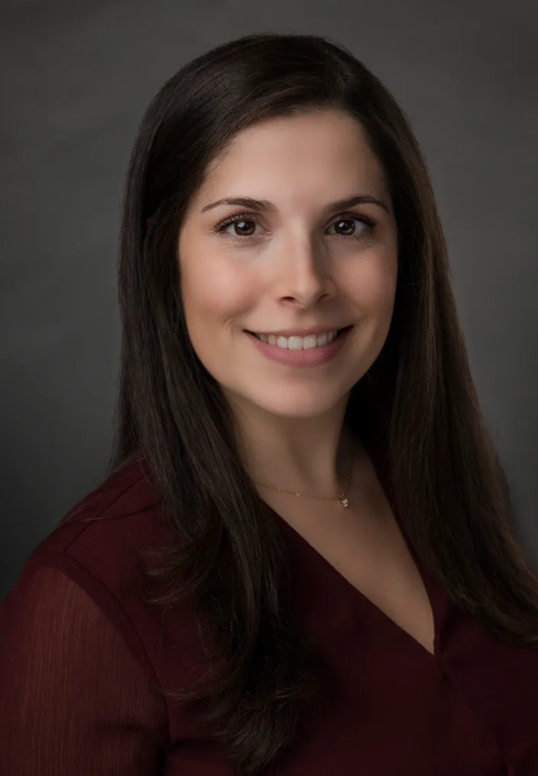 A woman in a red shirt is smiling for the camera.