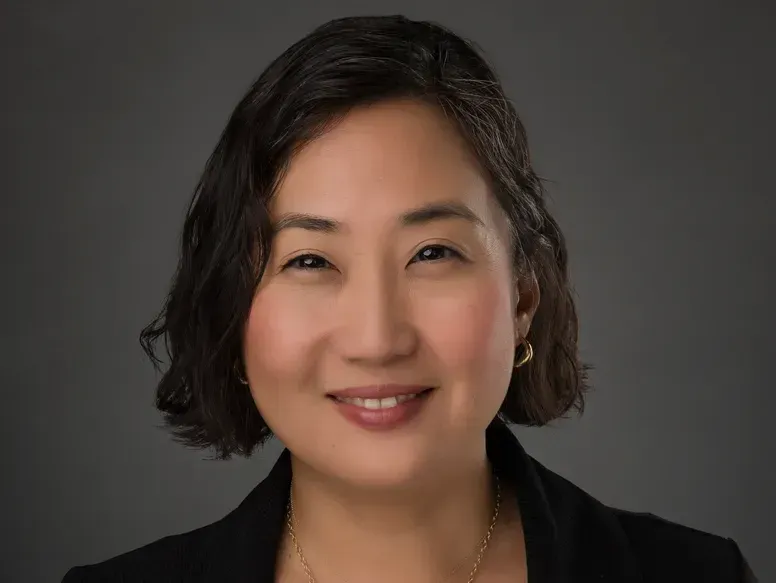 A woman in a black jacket is smiling for the camera.