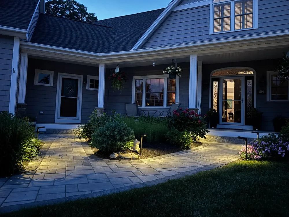 Night view of a gray house with pathway lighting along a stone walkway and front yard landscaping.