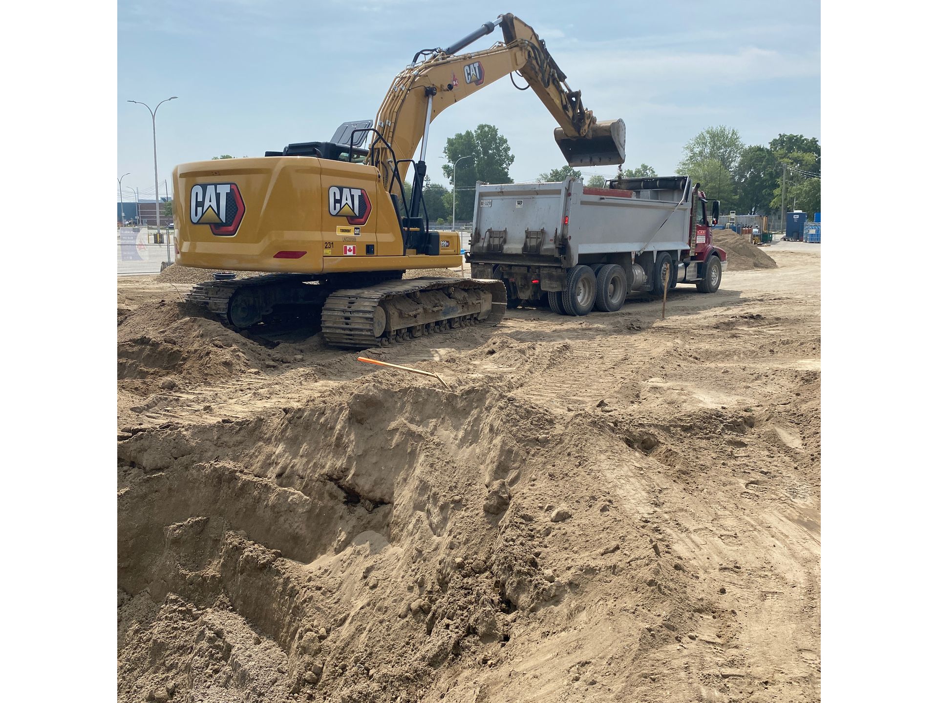 A cat excavator is loading dirt into a dump truck.