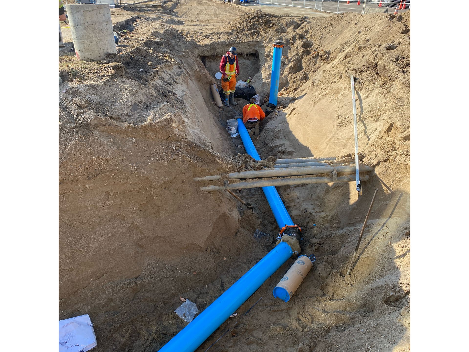 A group of men are working on a pipe in the dirt.