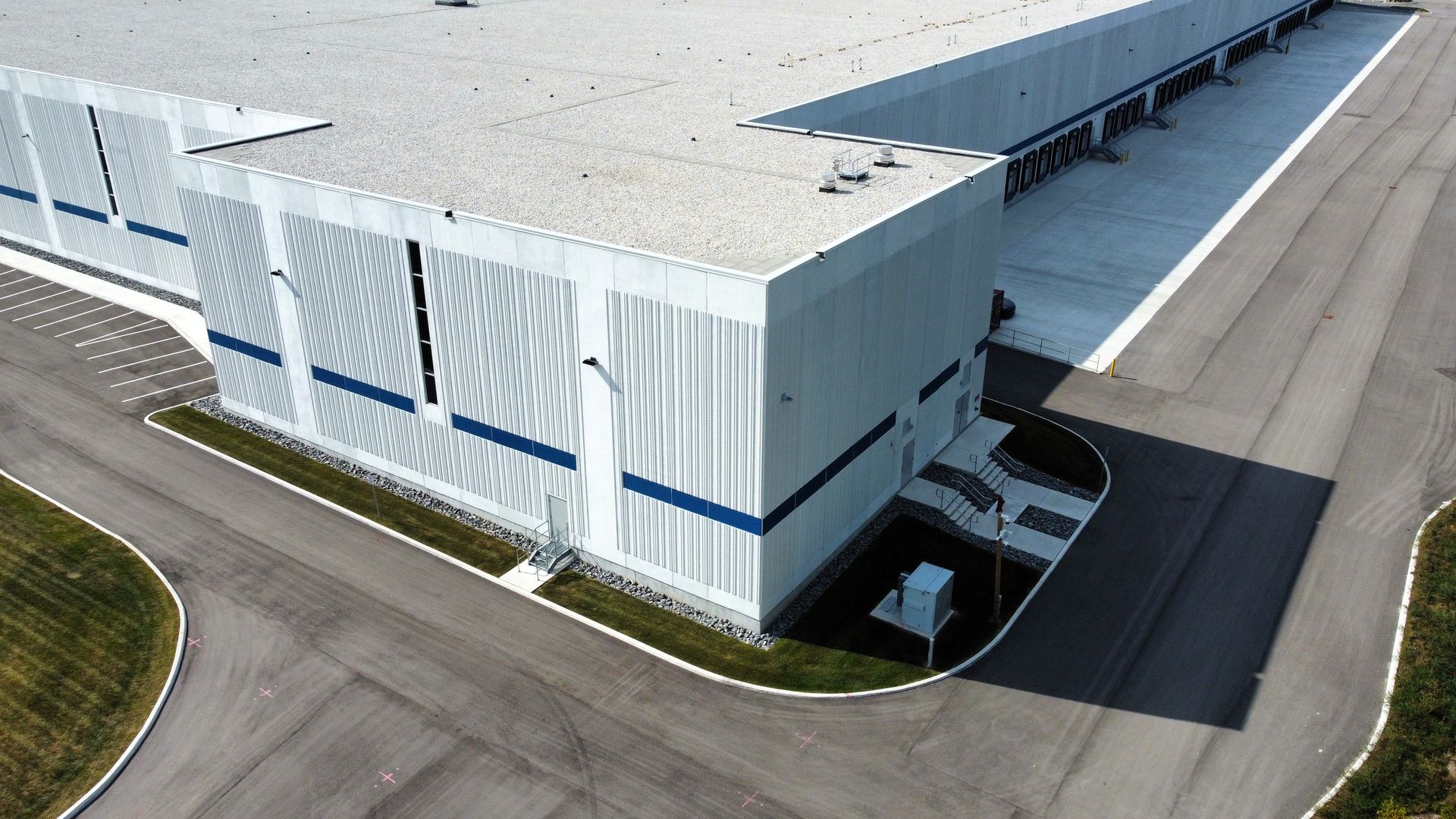 An aerial view of a large white building with blue stripes on the side.