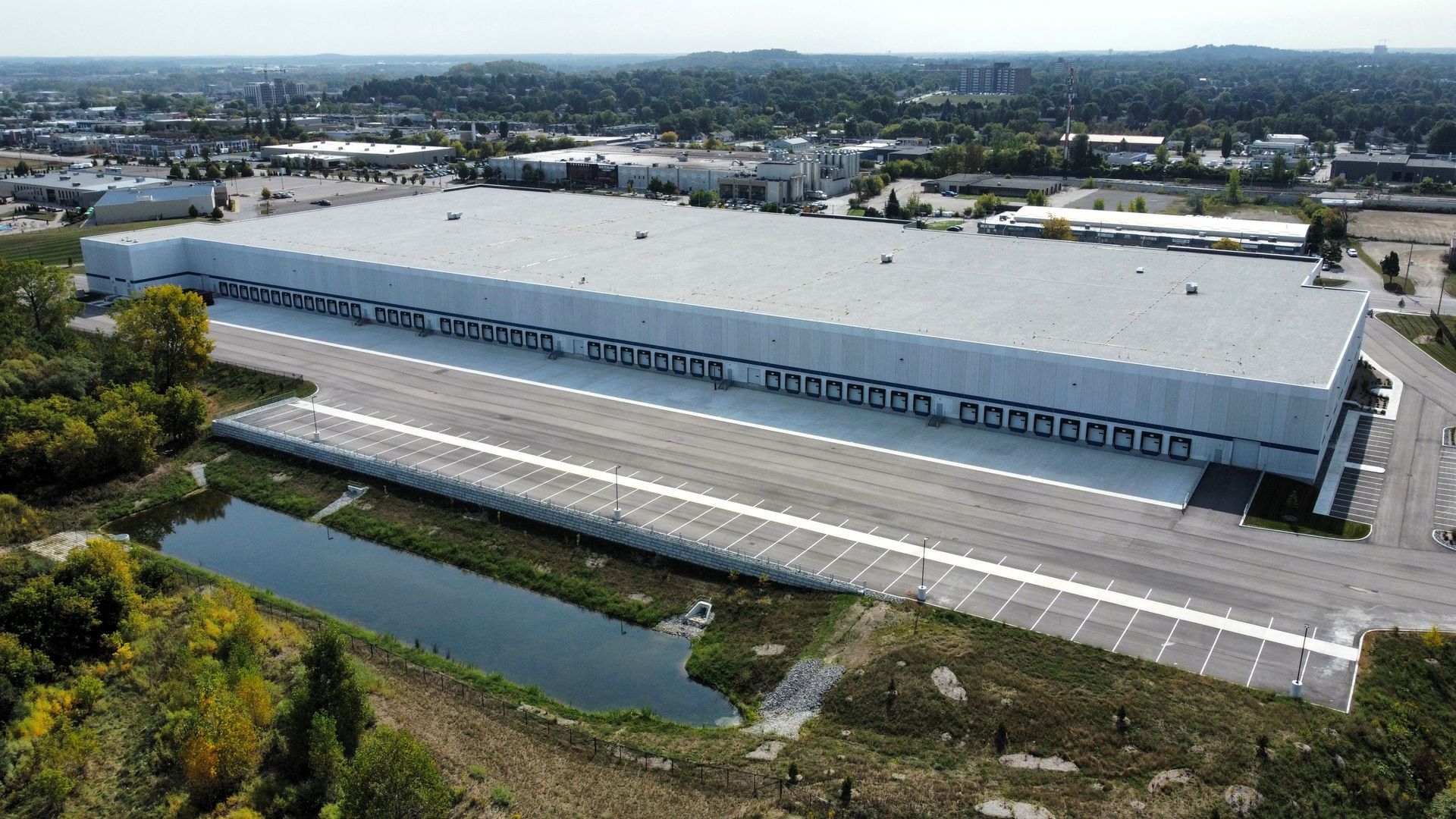 An aerial view of a large white building with a pond in front of it.
