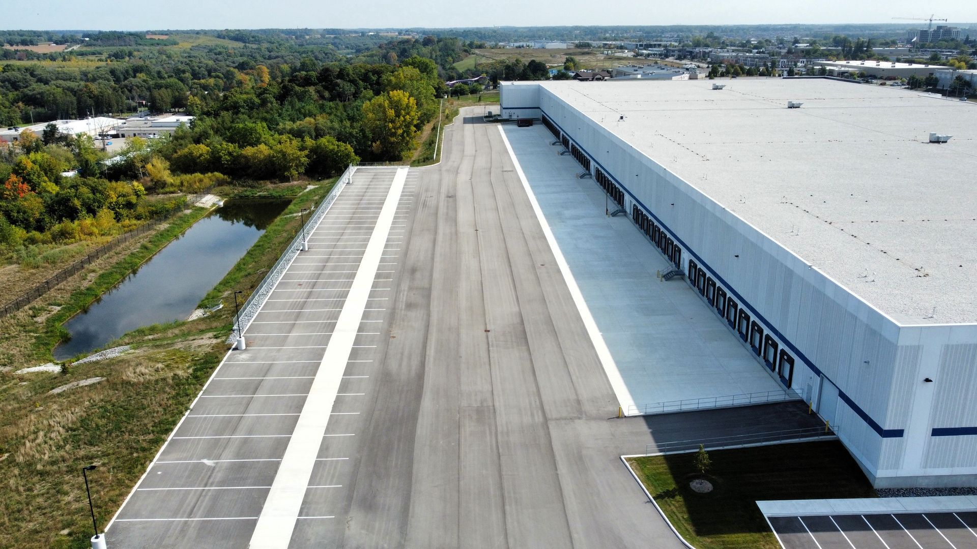 An aerial view of a large warehouse with a parking lot in front of it.