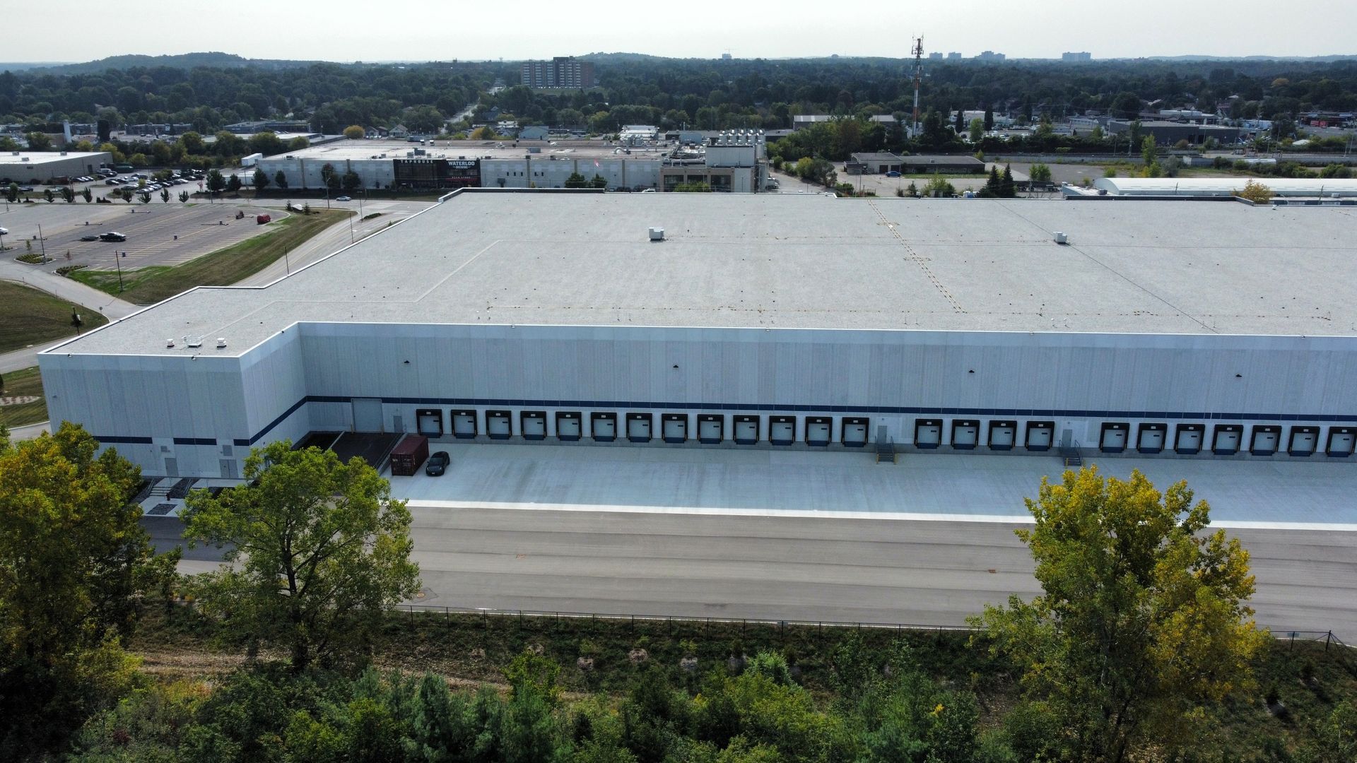 An aerial view of a large white building with a parking lot in front of it.