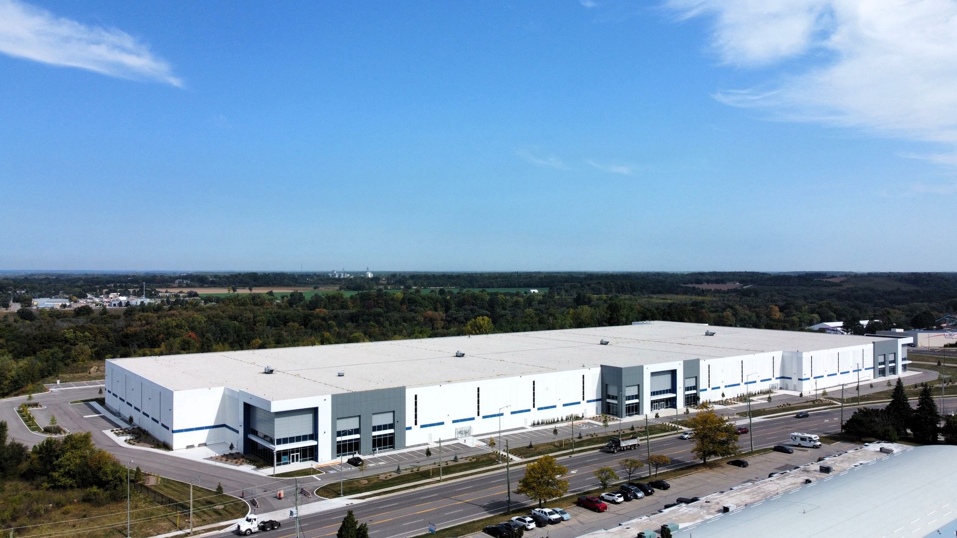 An aerial view of a large white building with a lot of cars parked in front of it.