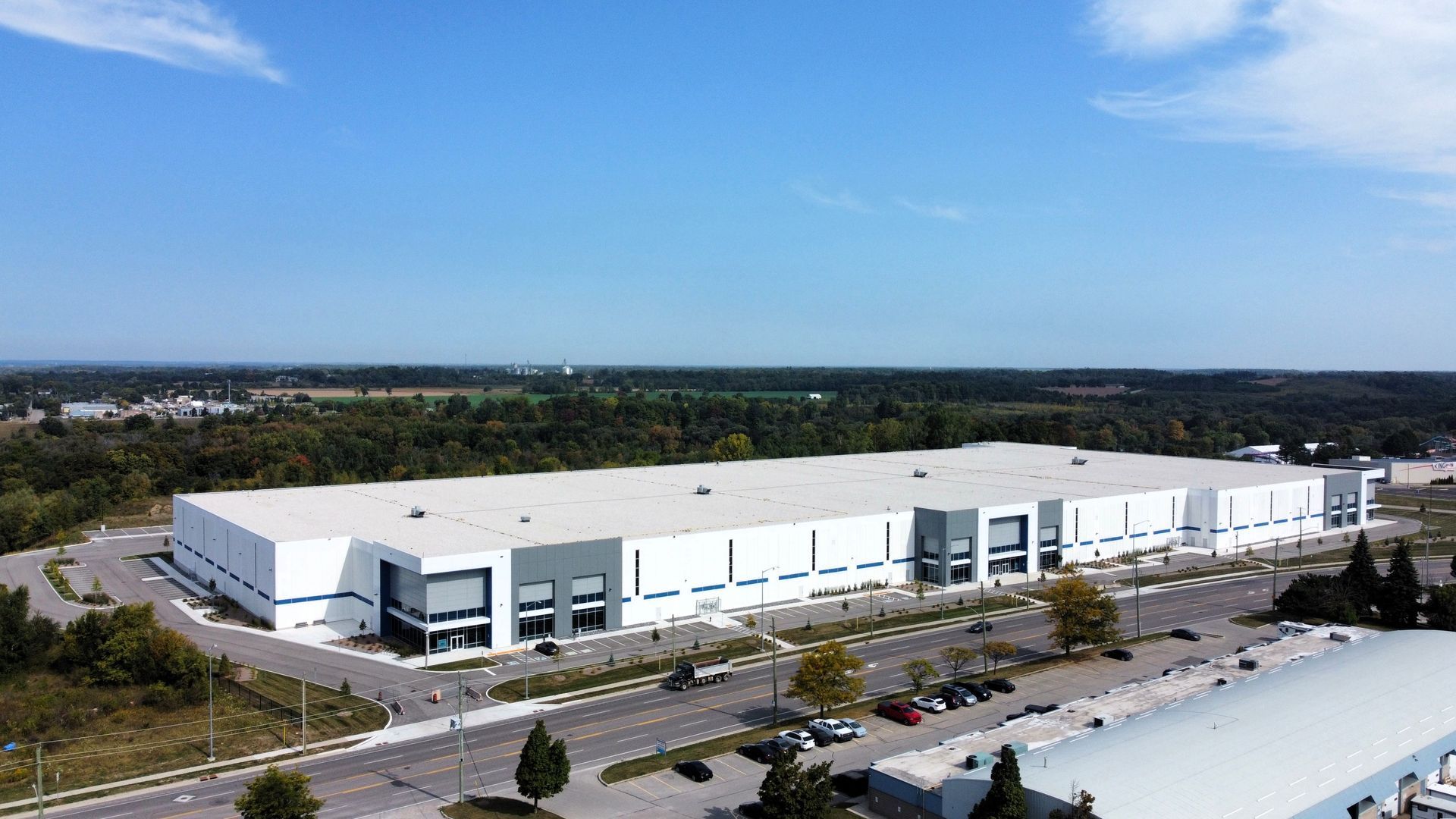An aerial view of a large white building with a lot of cars parked in front of it.