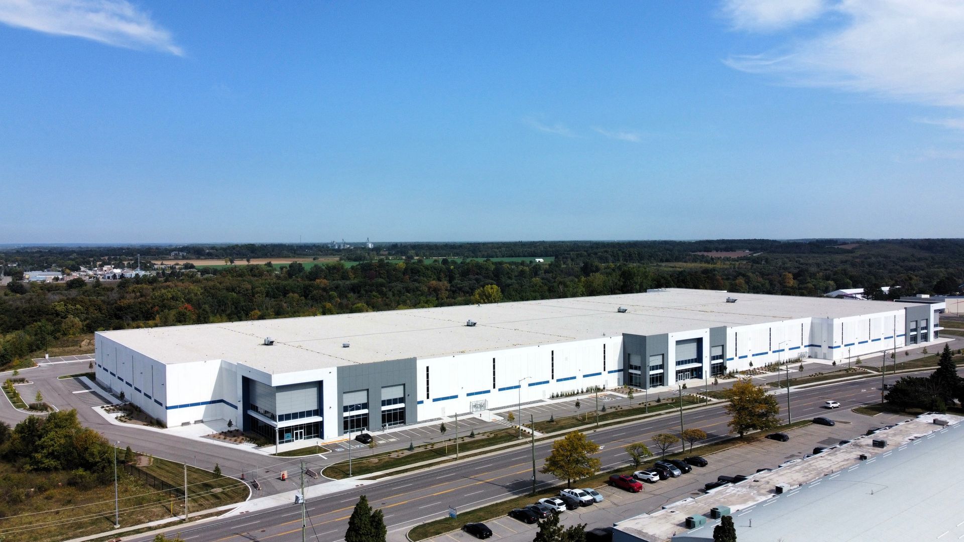 An aerial view of a large white building with a lot of cars parked in front of it.