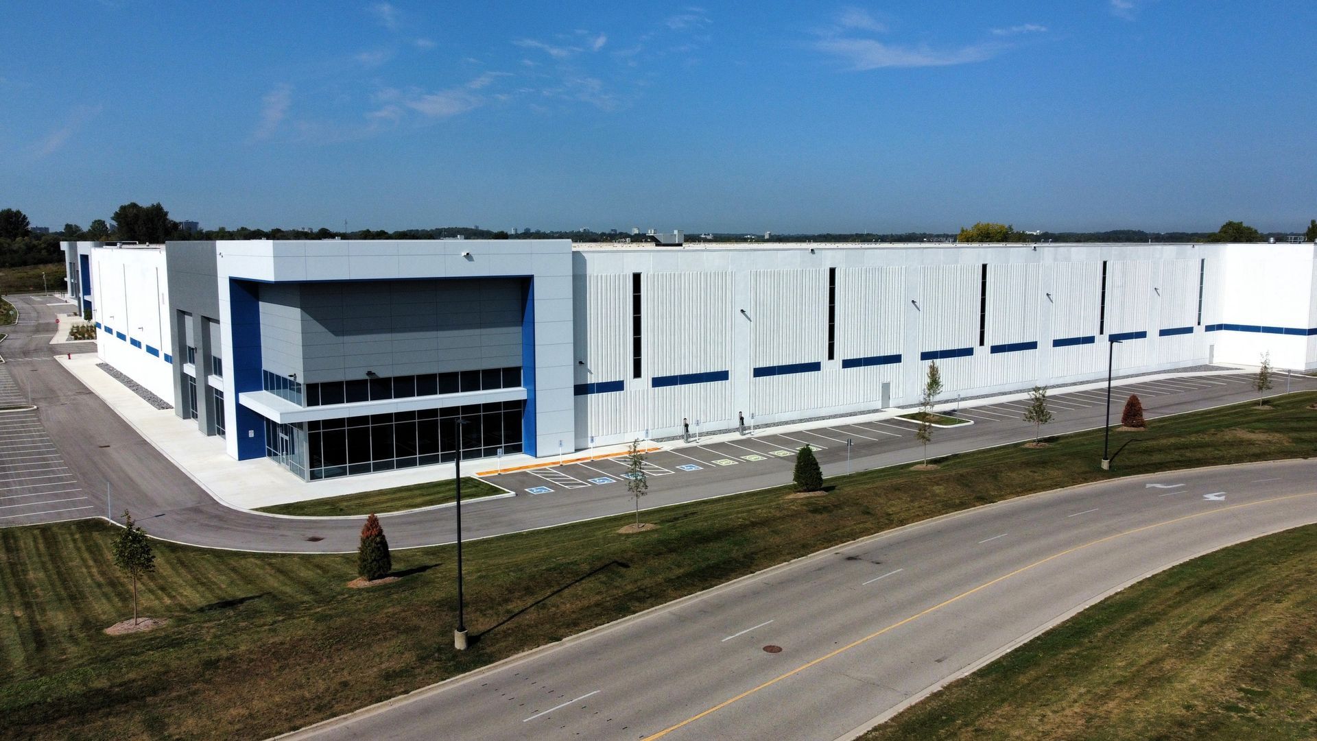 An aerial view of a large white and blue building next to a road.