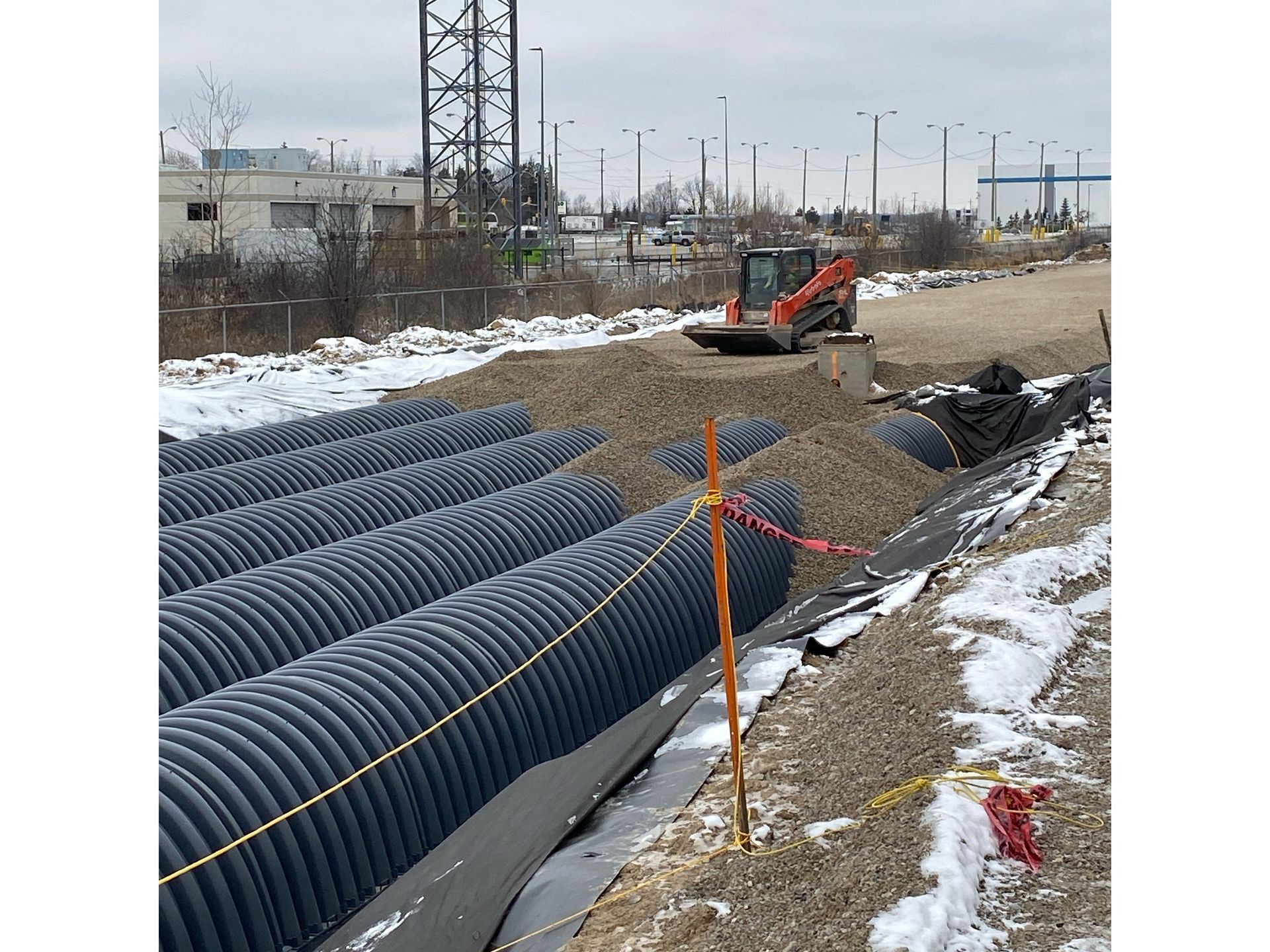 A construction site with a lot of pipes and a bulldozer.