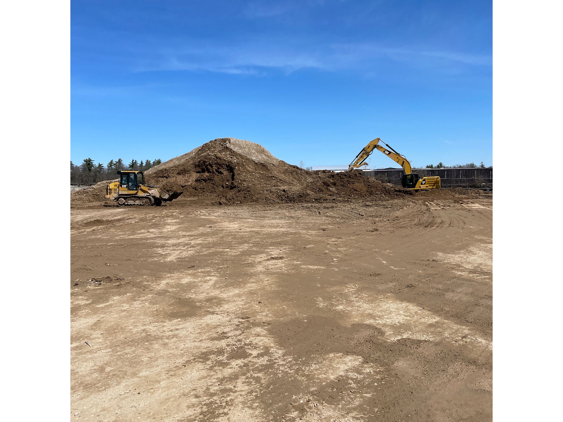 A large pile of dirt is being moved by a bulldozer.