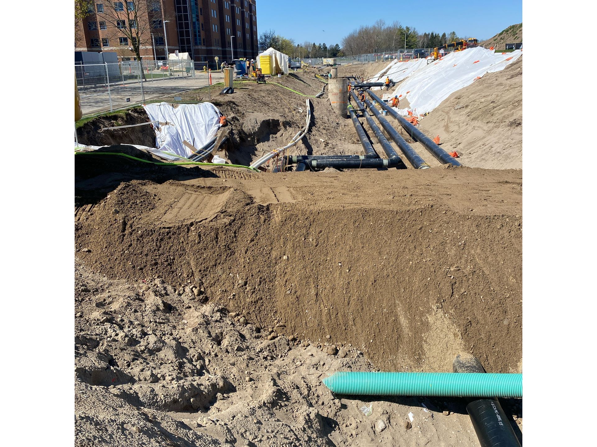 A bunch of pipes are laying in the dirt on a construction site.