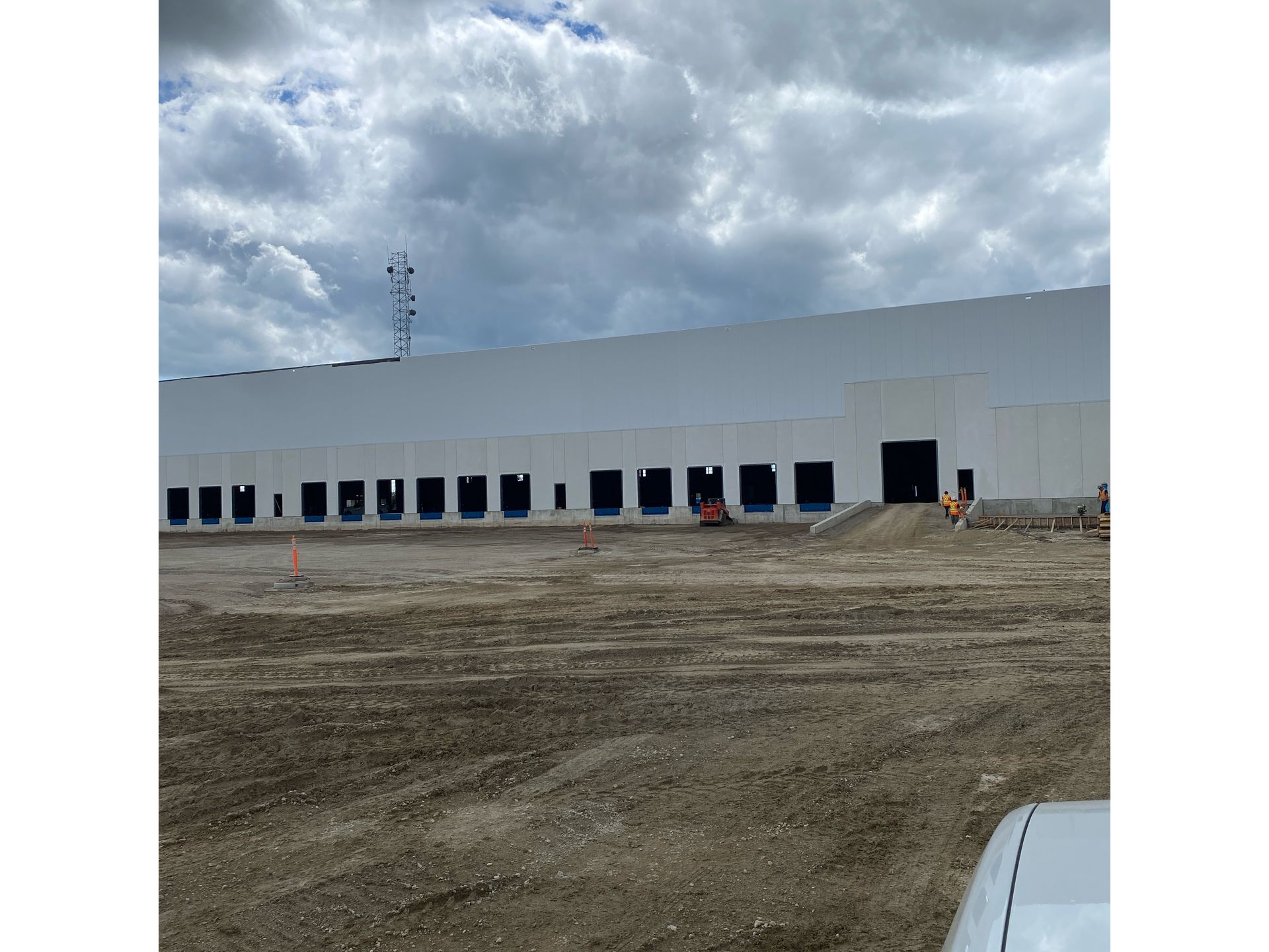 A large white building is being built in the middle of a dirt field.