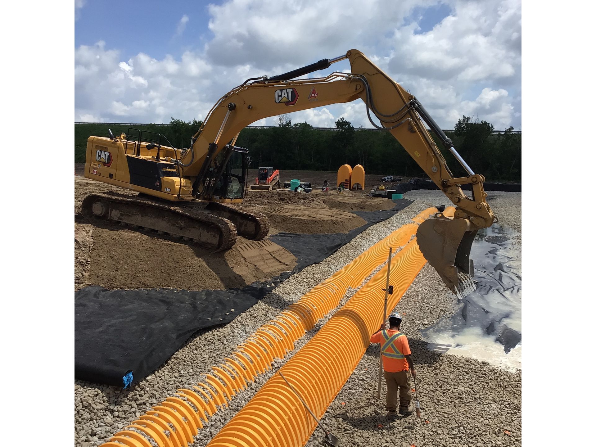 A man is standing next to a large excavator on a construction site.