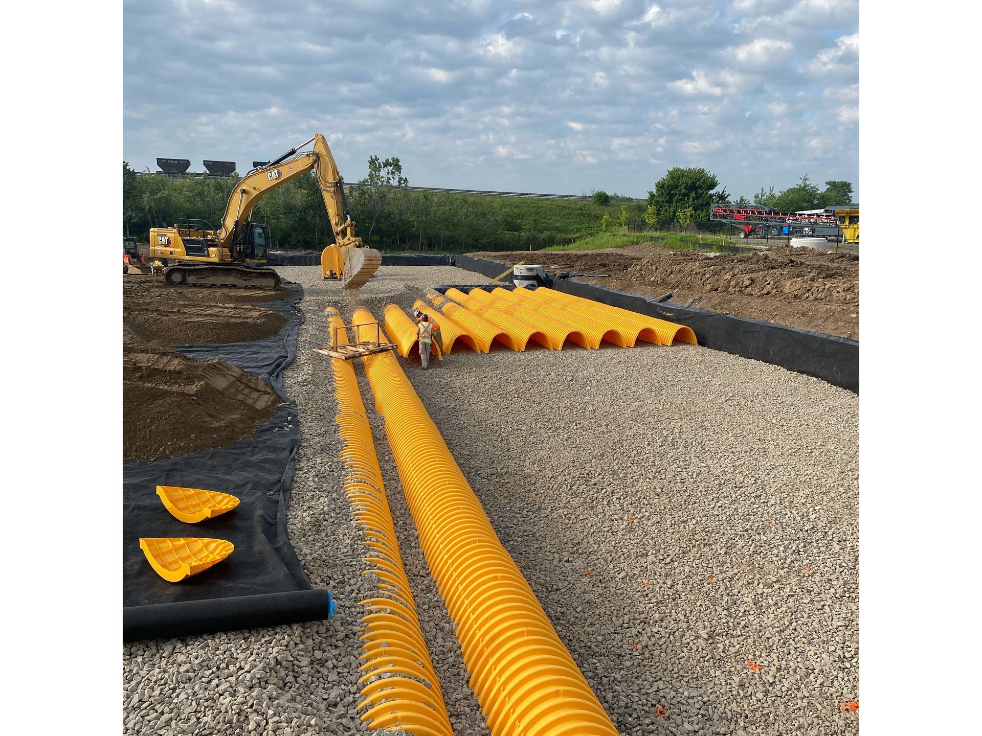 A construction site with yellow pipes and a bulldozer in the background.