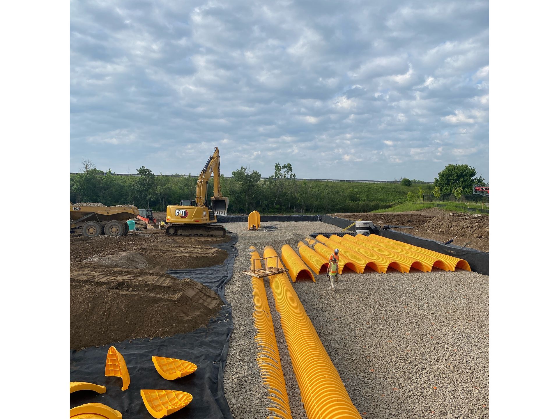 A construction site with a lot of yellow pipes and a bulldozer.