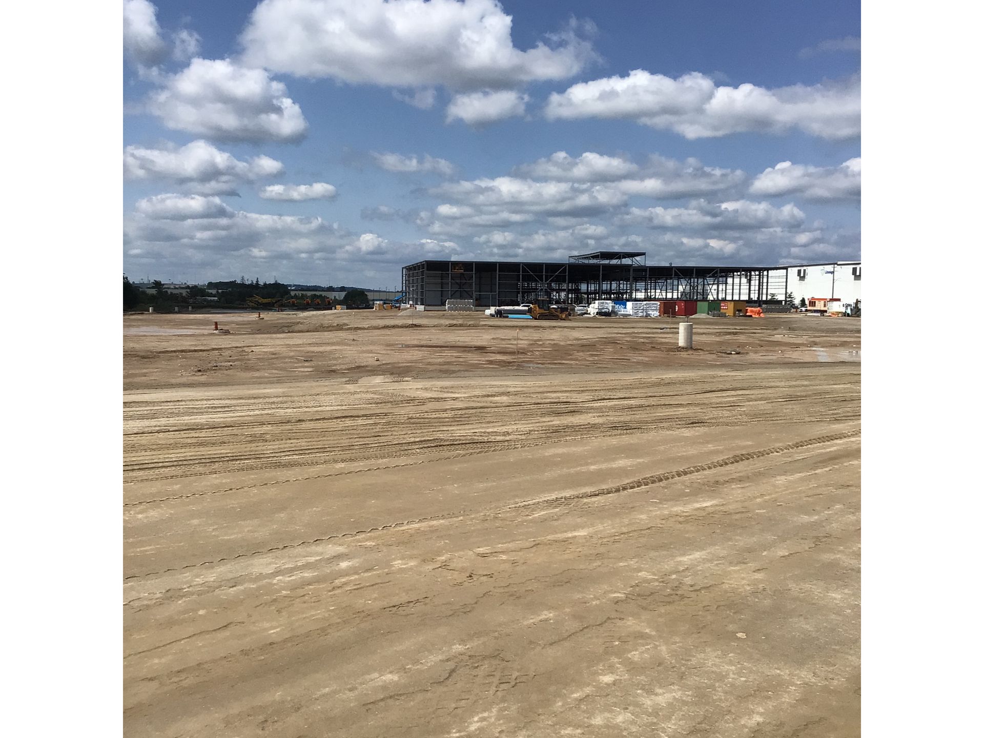 A large building is being built in the middle of a dirt field.