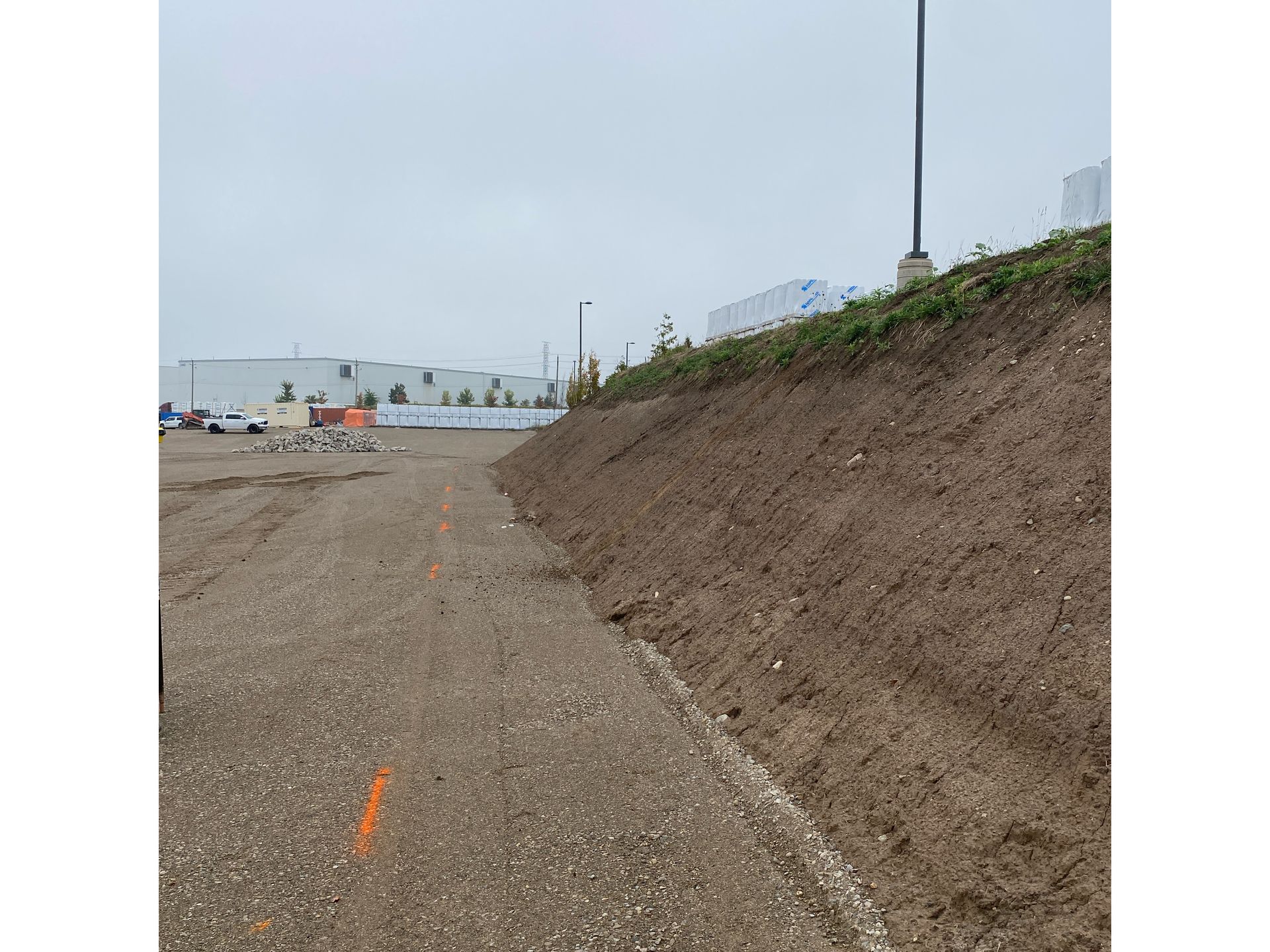 A dirt road with a large pile of dirt on the side of it.