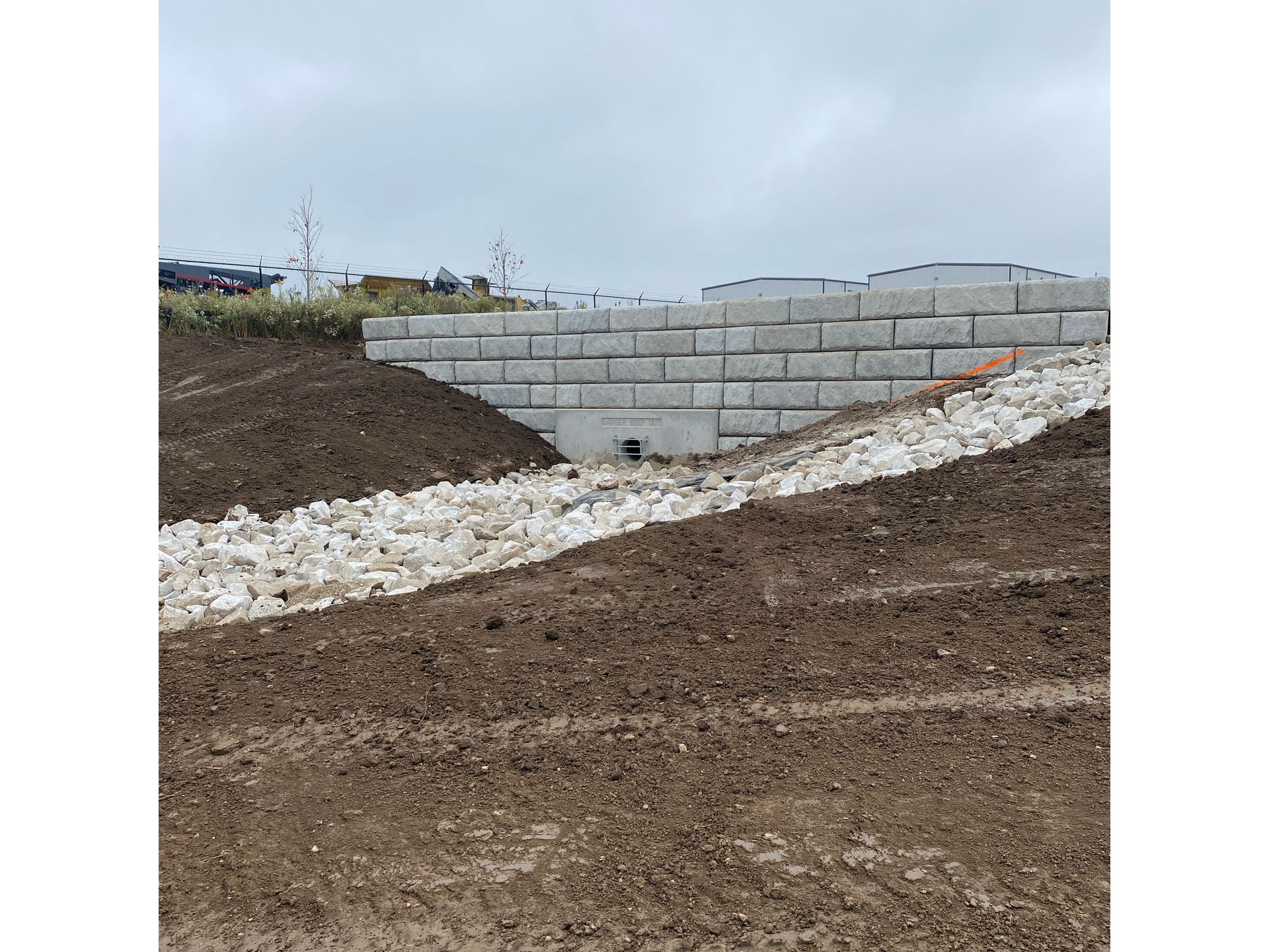 A large brick wall is sitting on top of a dirt hill.