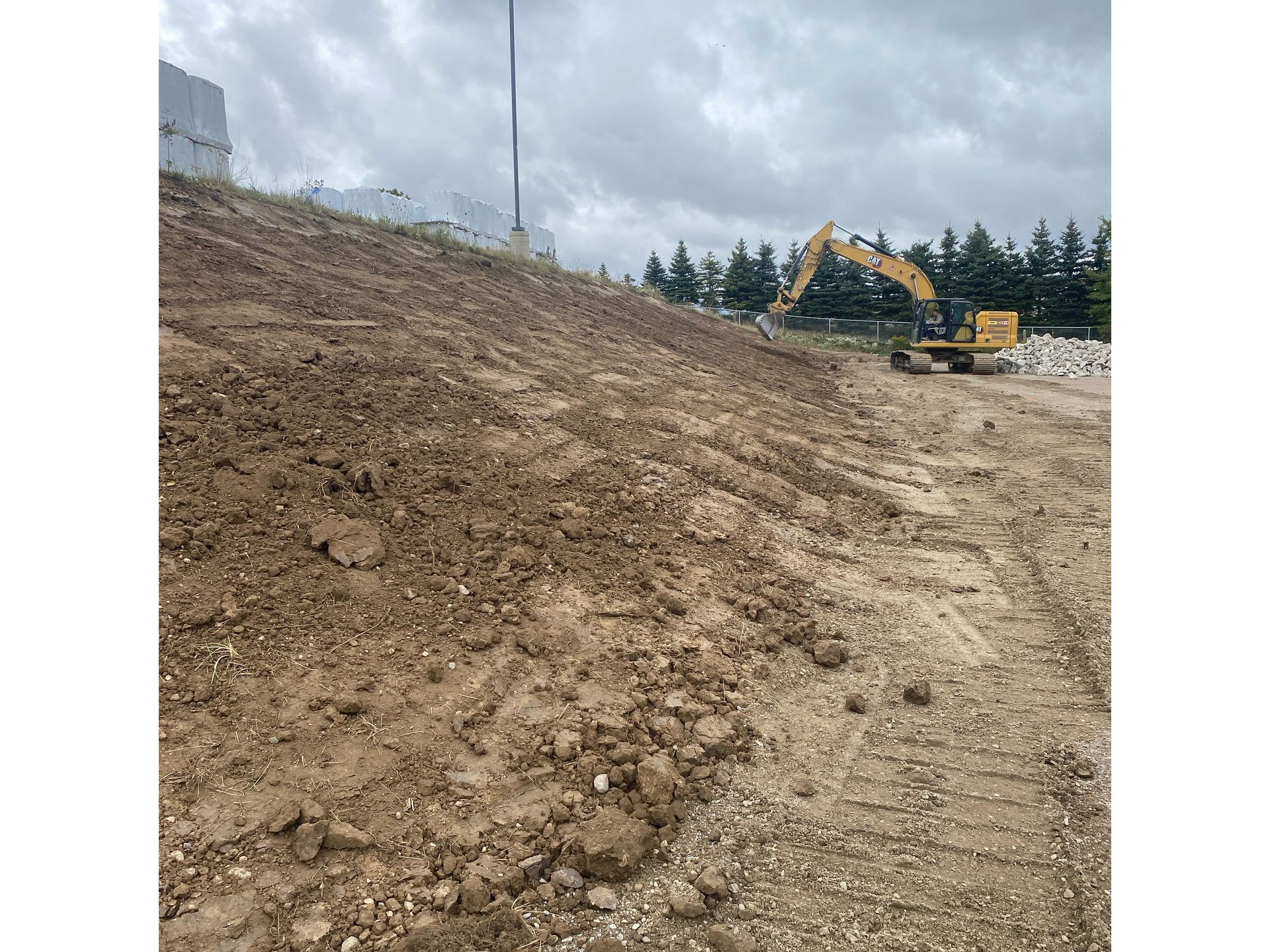 A large excavator is working on a dirt hill.