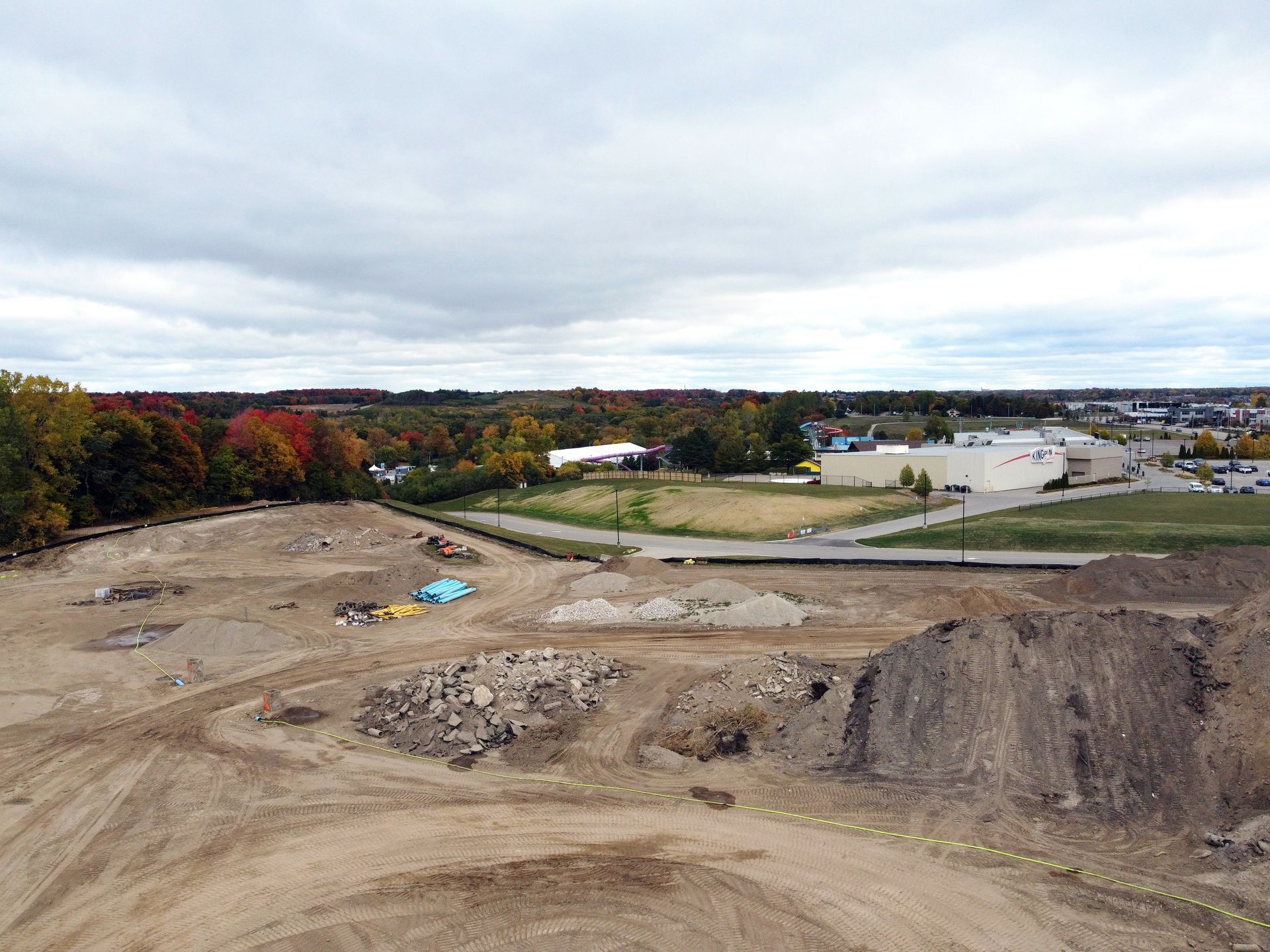 An aerial view of a construction site with a lot of dirt and trees in the background.