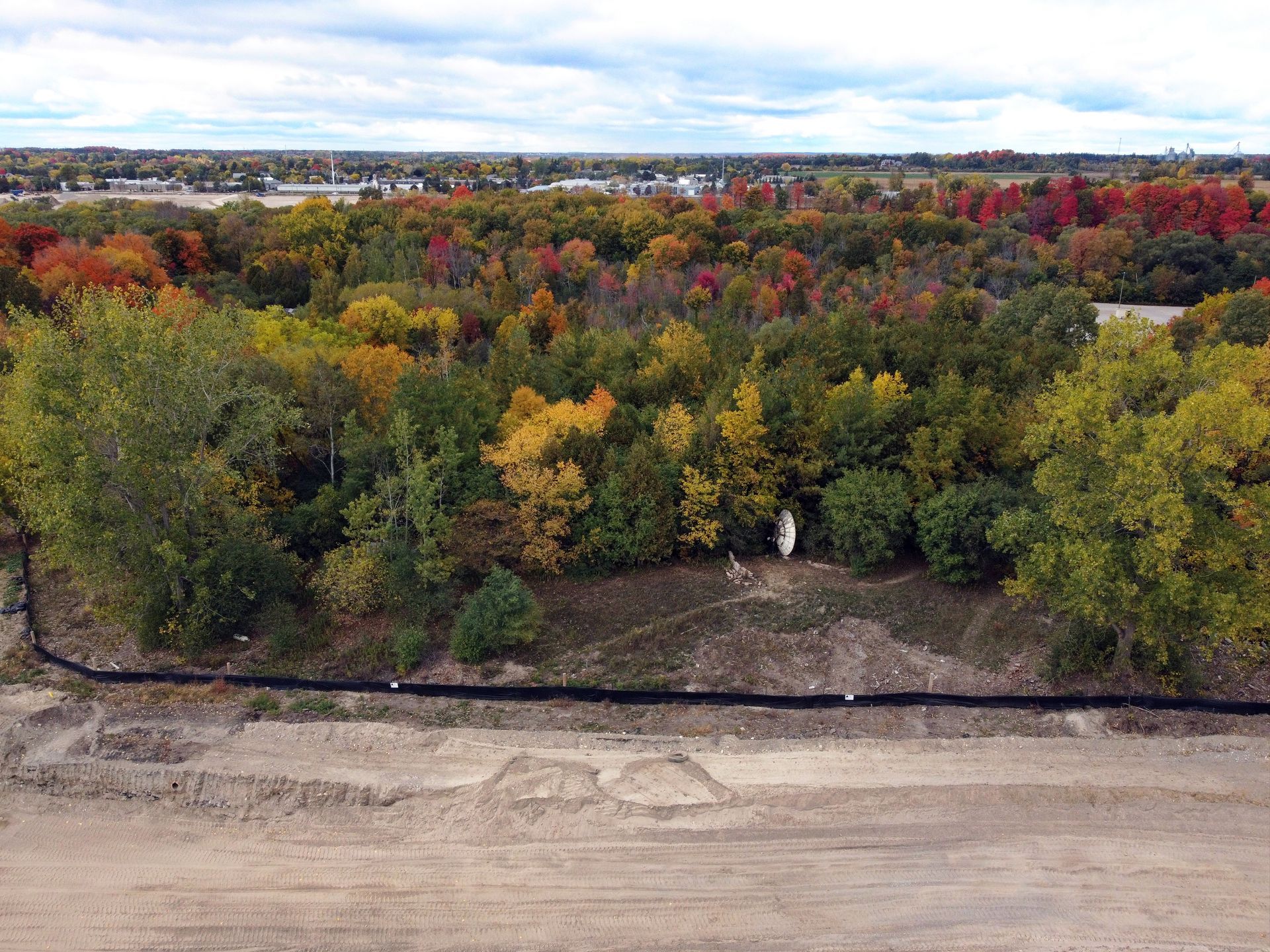 An aerial view of a forest with trees changing colors in the fall.