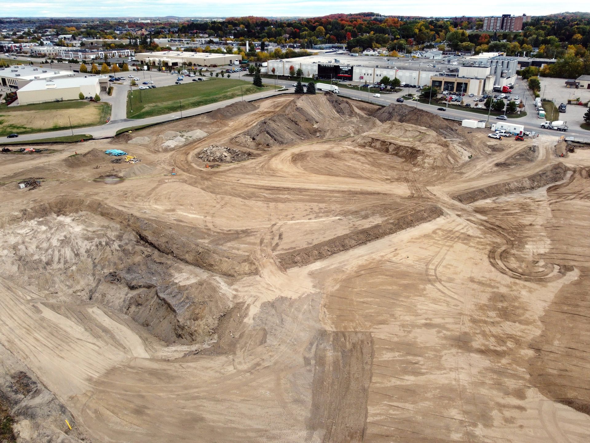 An aerial view of a construction site with a lot of dirt and buildings in the background.