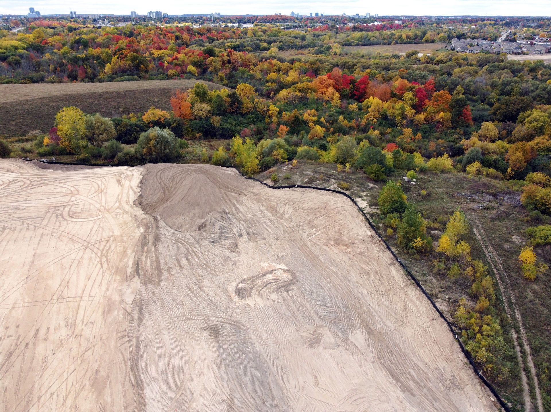 An aerial view of a dirt field with trees in the background.