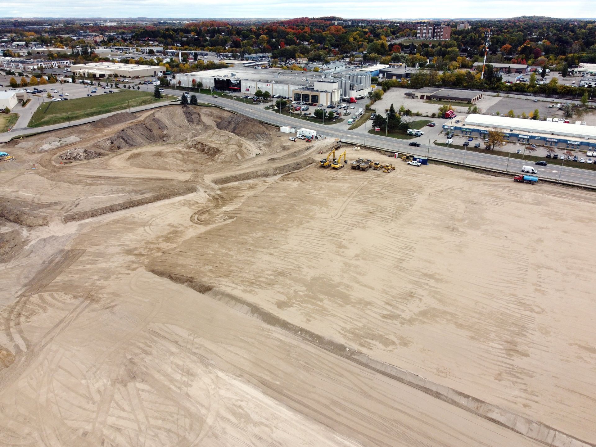 An aerial view of a construction site with a lot of dirt and buildings in the background.