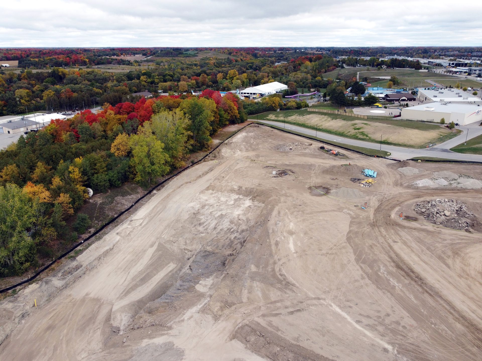 An aerial view of a large dirt field with trees in the background.
