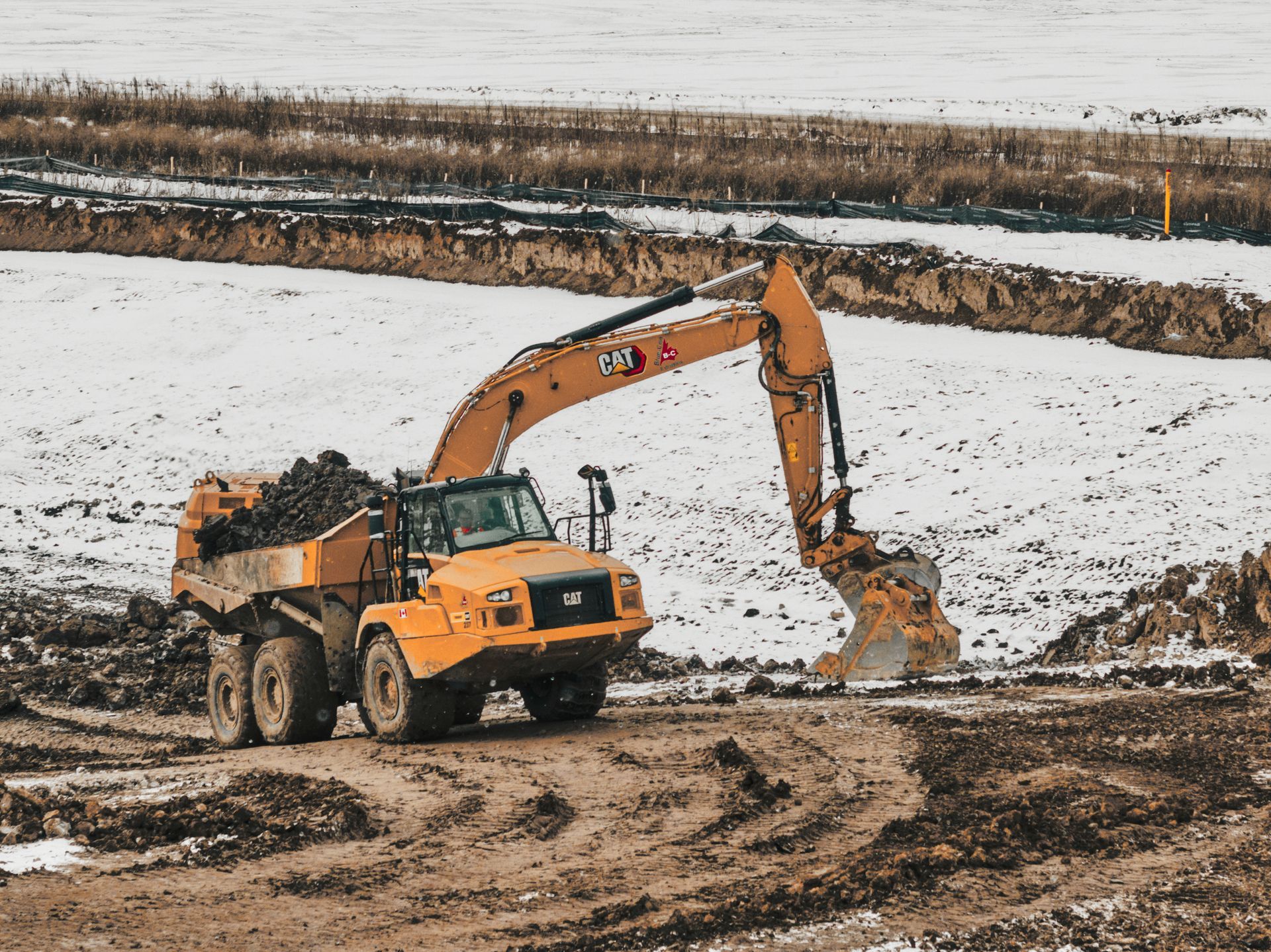 Blue-Con yellow excavator is loading dirt into a dump truck in St. Thomas