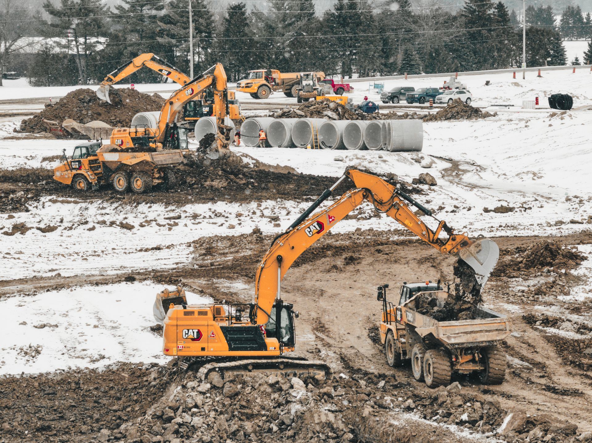 A group of construction vehicles are working on a construction site in the snow  in St. Thomas
