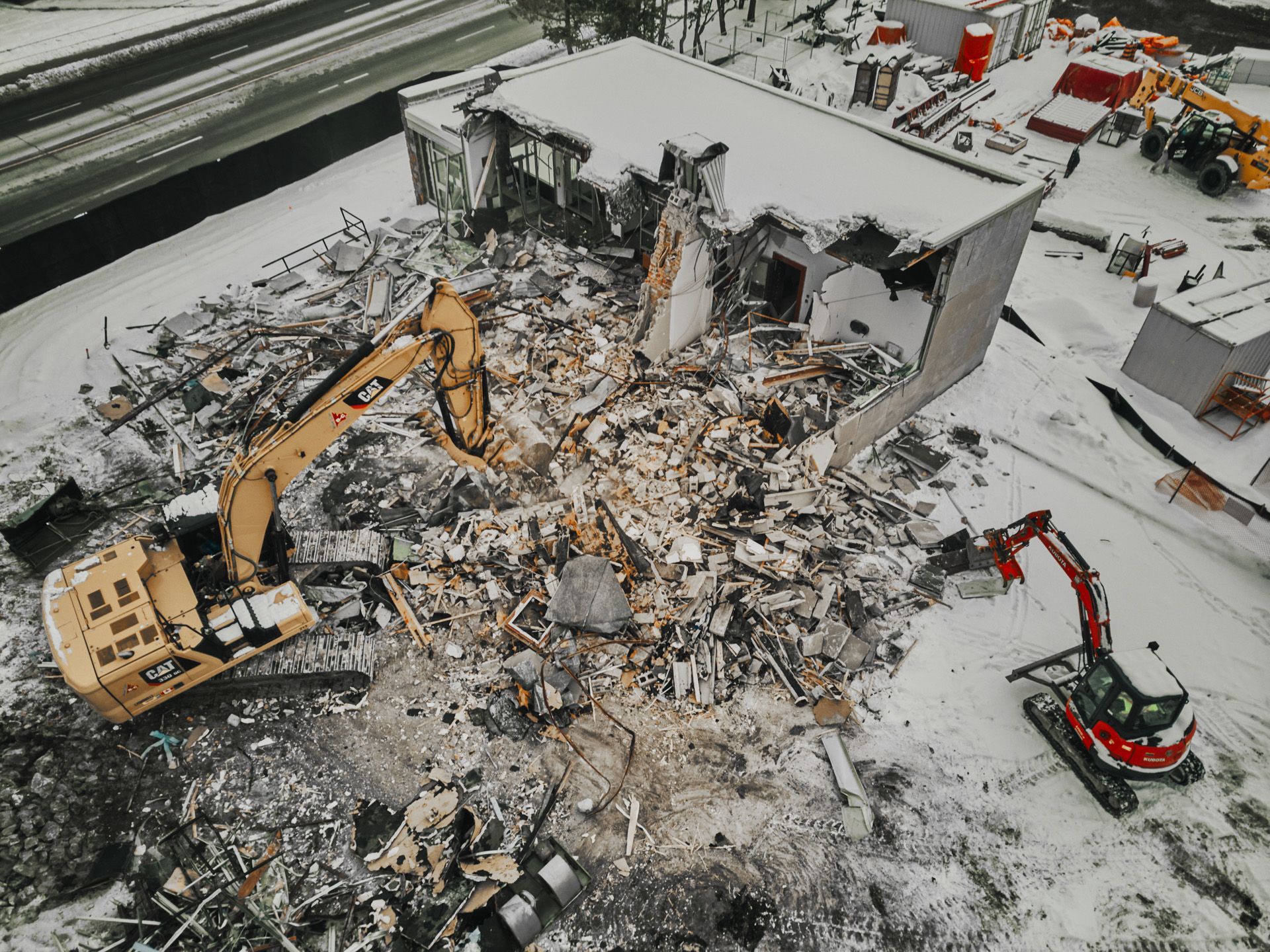 An aerial view of a building being demolished in the snow.