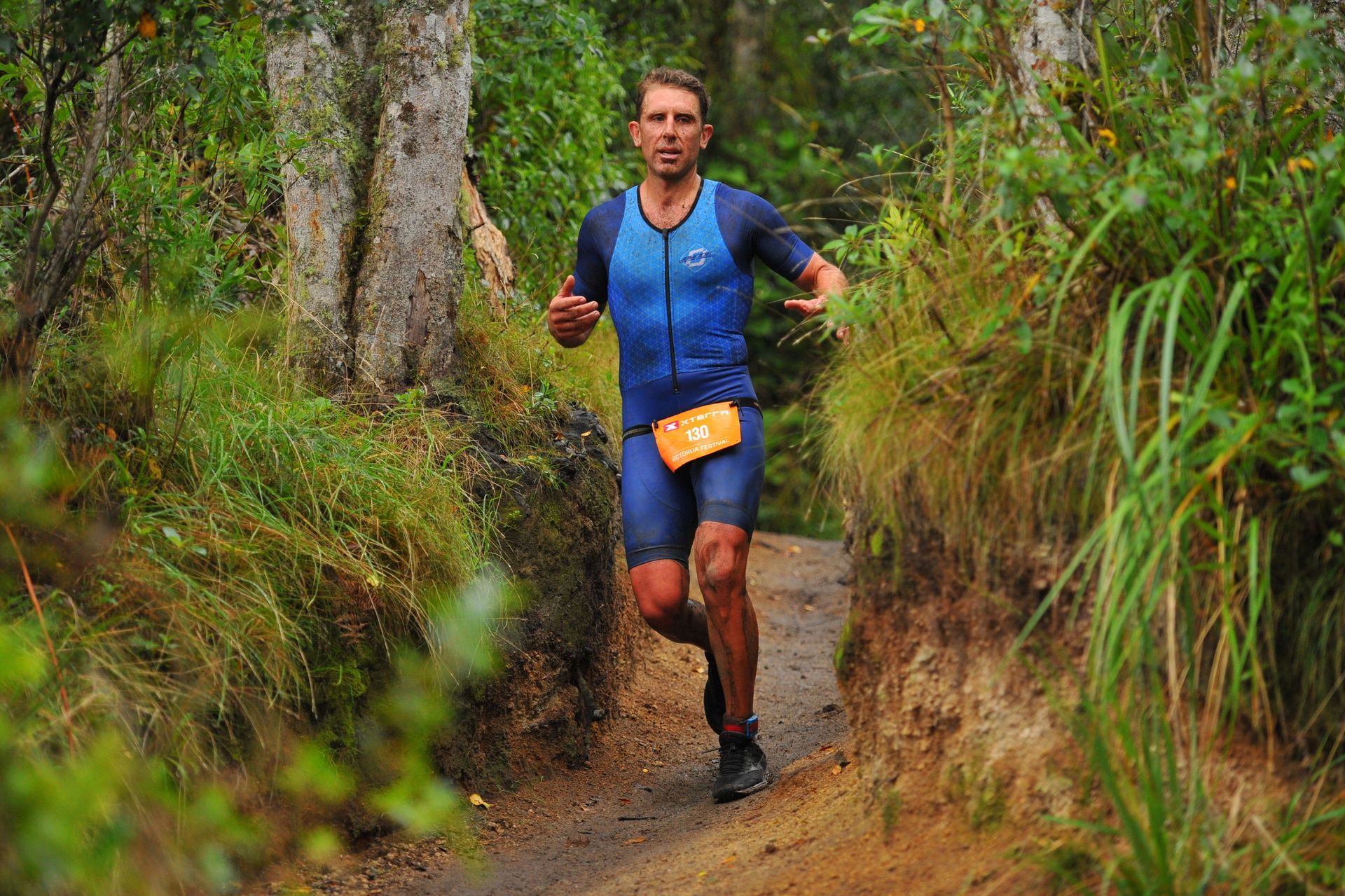 A man is running down a path in the woods.