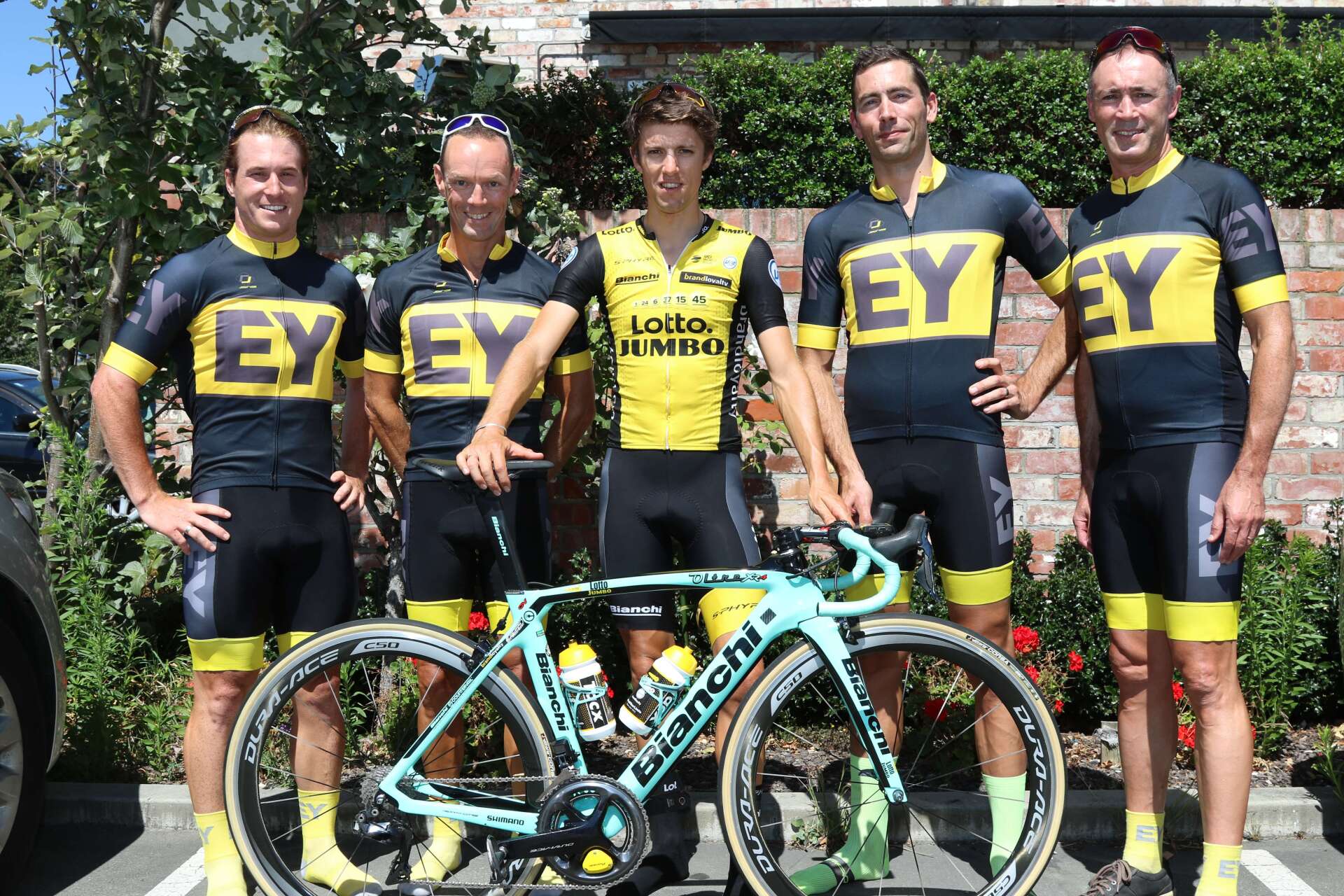 A group of men standing next to a bicycle wearing ey jerseys