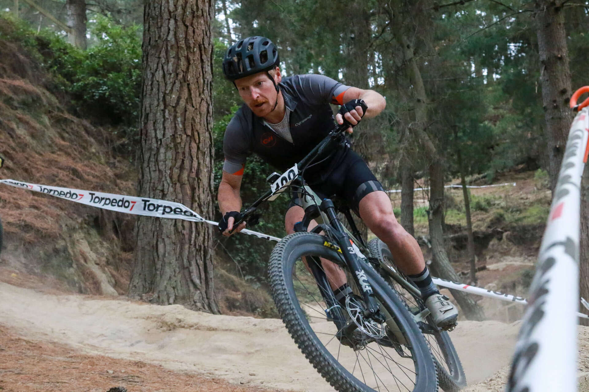 A man is riding a bike on a dirt road in the woods.